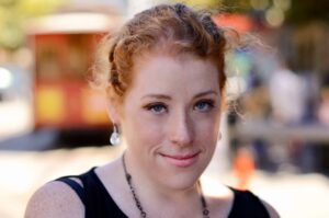 A pretty young woman with red hair and freckles on a blurred background