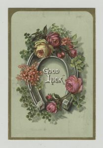 An image of a horseshoe wreath with large roses and the words "Good Luck" written inside.